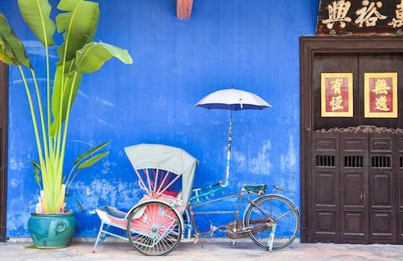 Bicycle rickshaw against a blue wall in Malaysia